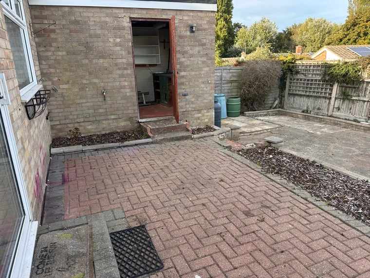The block paving cleared back to the brick and the border beside it raked off, later in the same job