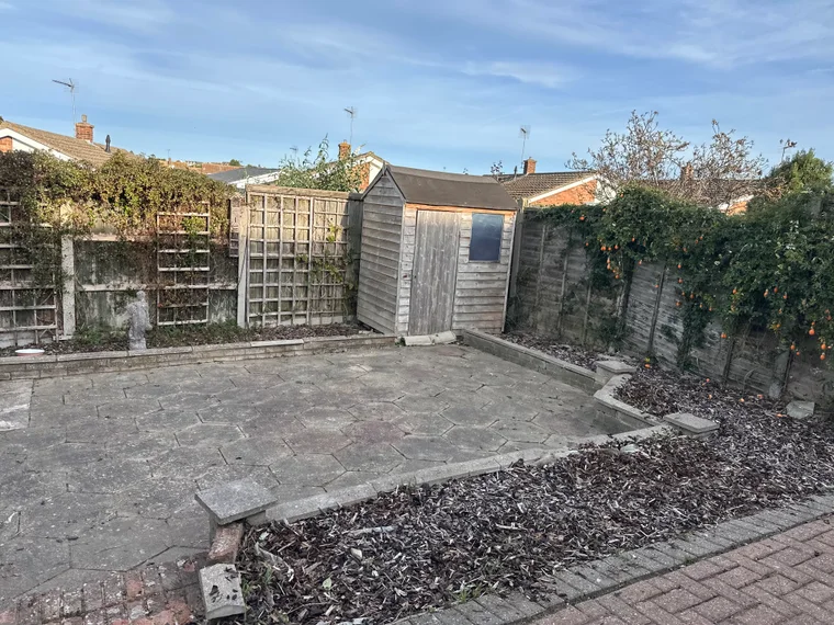 The same patio cleared back to bare slabs, with the raised bed beside it taken down to fresh bark